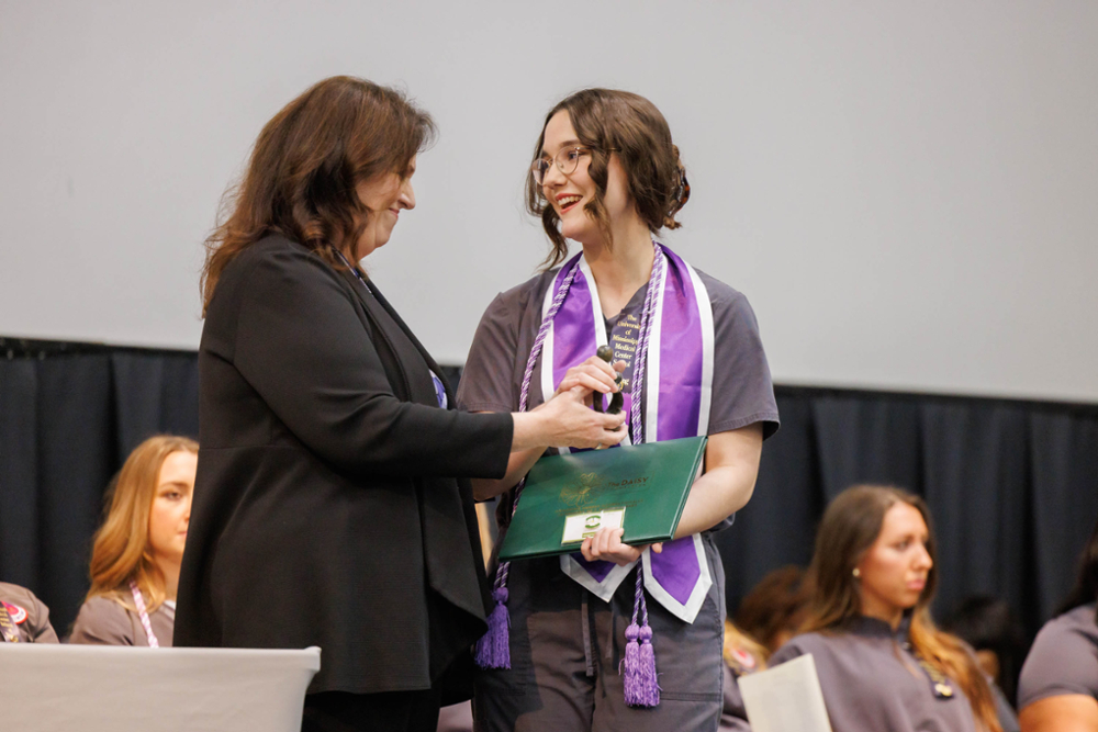 Laura Baker receives the DAISY in Training Student Nurse award from the dean during her Pinning ceremony.
